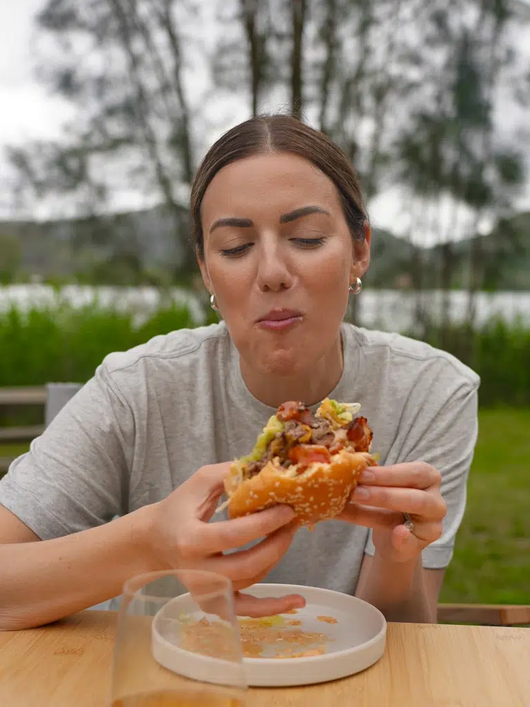 Nic taking a satisfying bite of a beef and bacon burger.