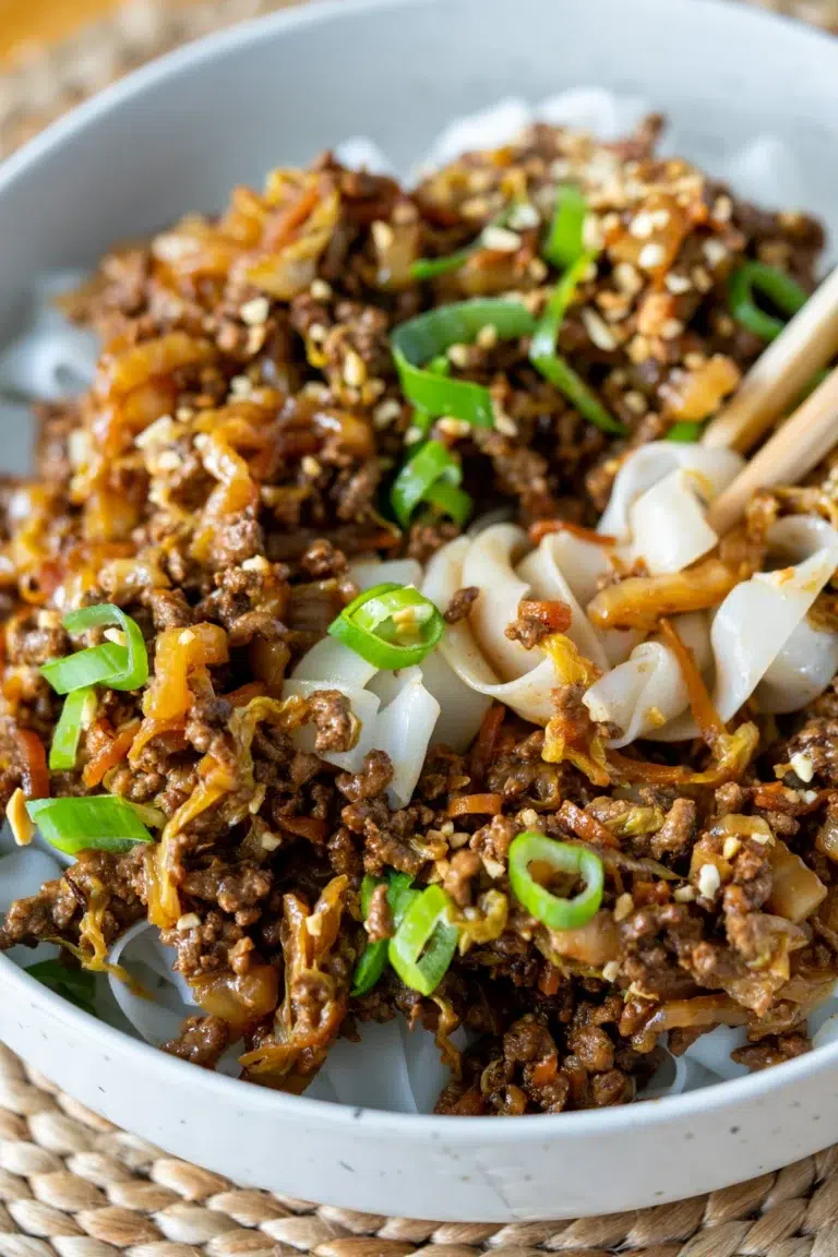 Close-up of Sticky Hoisin Beef with chopsticks in beef and noodles