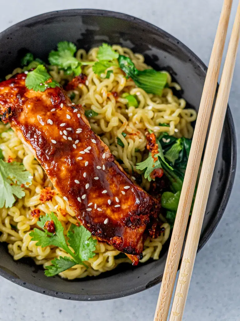 Overhead shot of a bowl of glazed miso salmon with ramen noodles, served with chopsticks.