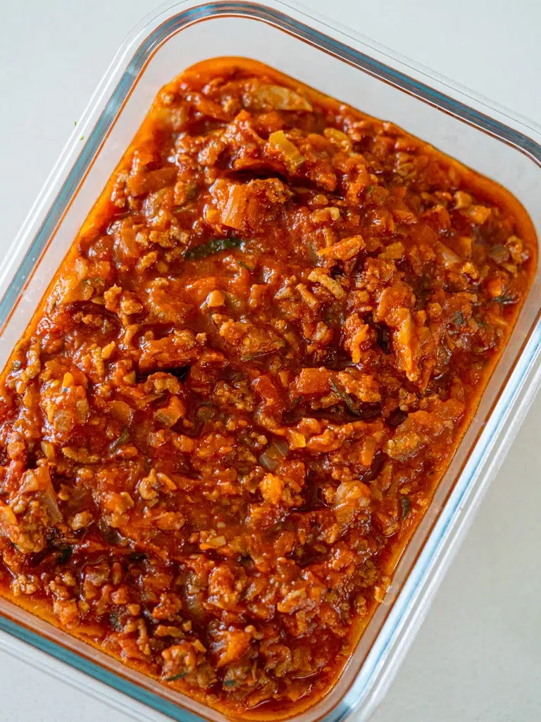 Close-up of hidden vegetable Bolognese sauce stored in a glass container, showcasing its rich texture and chunky vegetables.