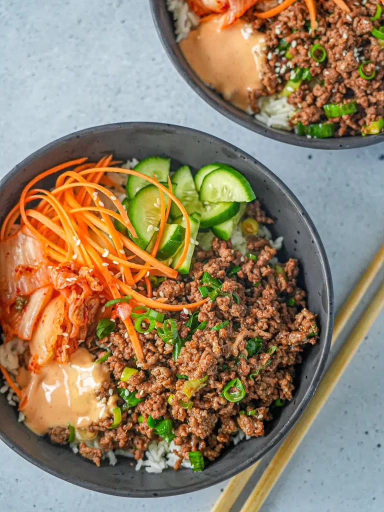Overhead shot of a flavorful Korean beef rice bowl with garnishes.