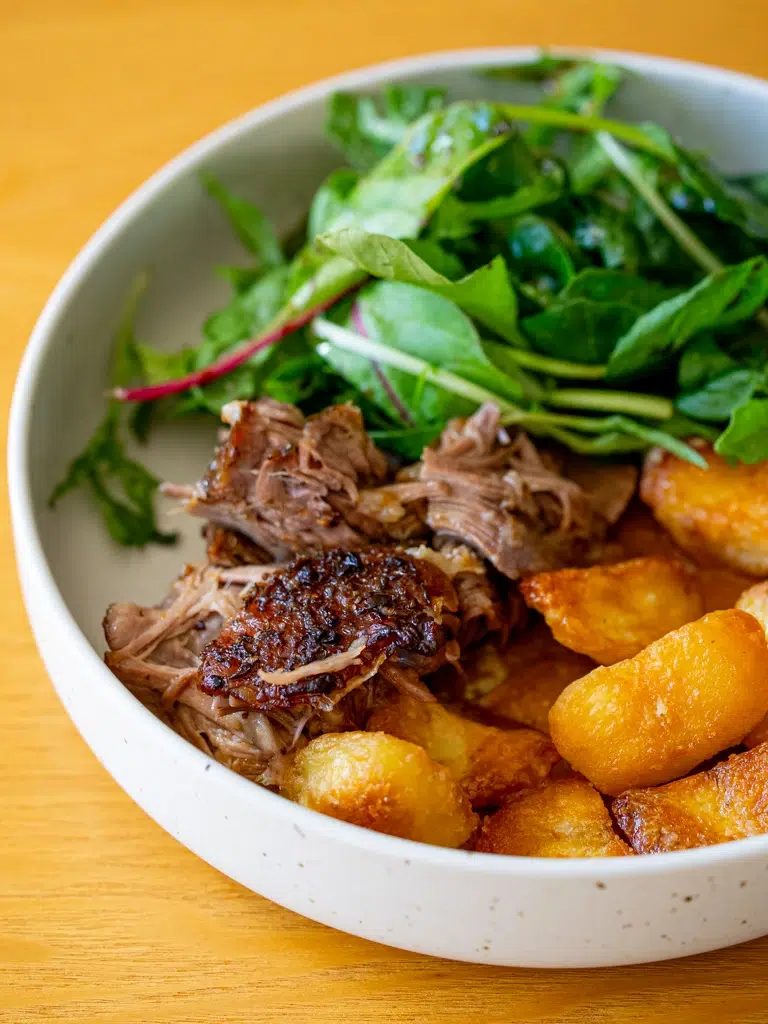Plated Rosemary Garlic Lamb Shoulder with gravy on a white plate.
