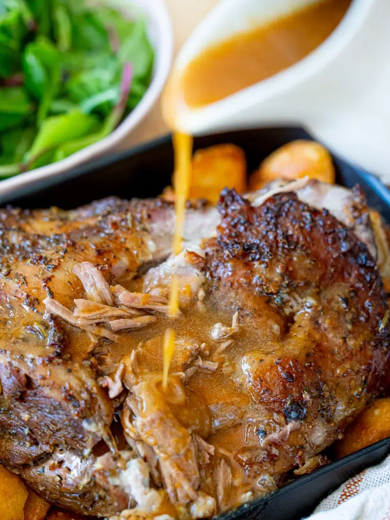 Gravy being poured over Rosemary Garlic Lamb shoulder